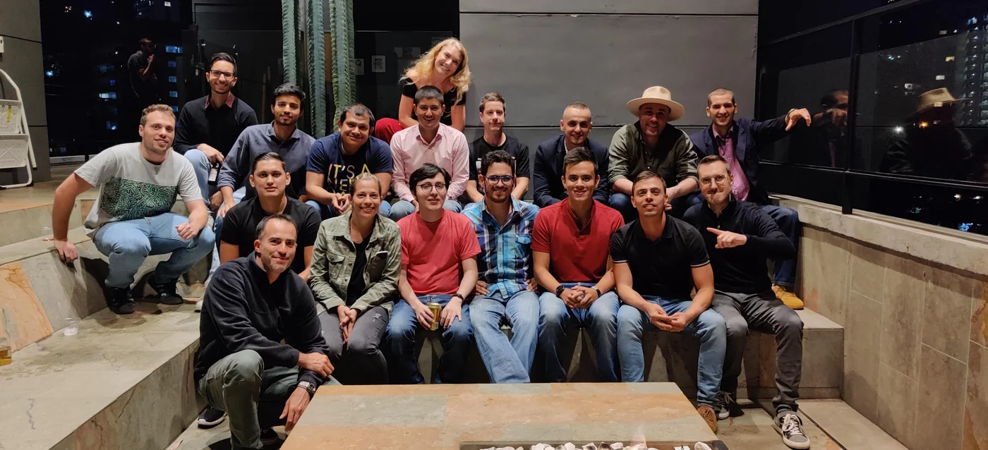 Around seventeen Eventtia team members gathered on a rooftop terrace at night, fire pit in front, December 2019.