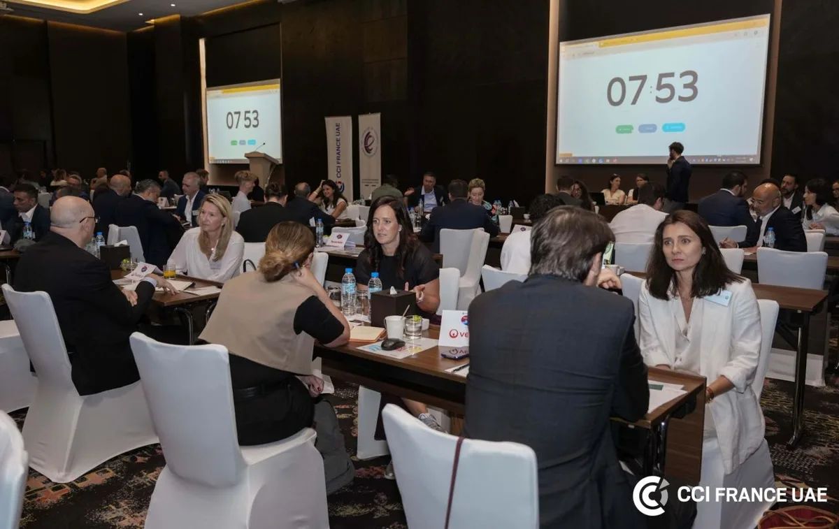 B2B matchmaking session at the CCI France UAE Working Together Forum in Dubai, attendees seated at tables with countdown timers projected on screens.