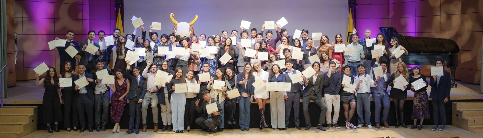Universidad de los Andes students on stage holding their certificates at a ceremony