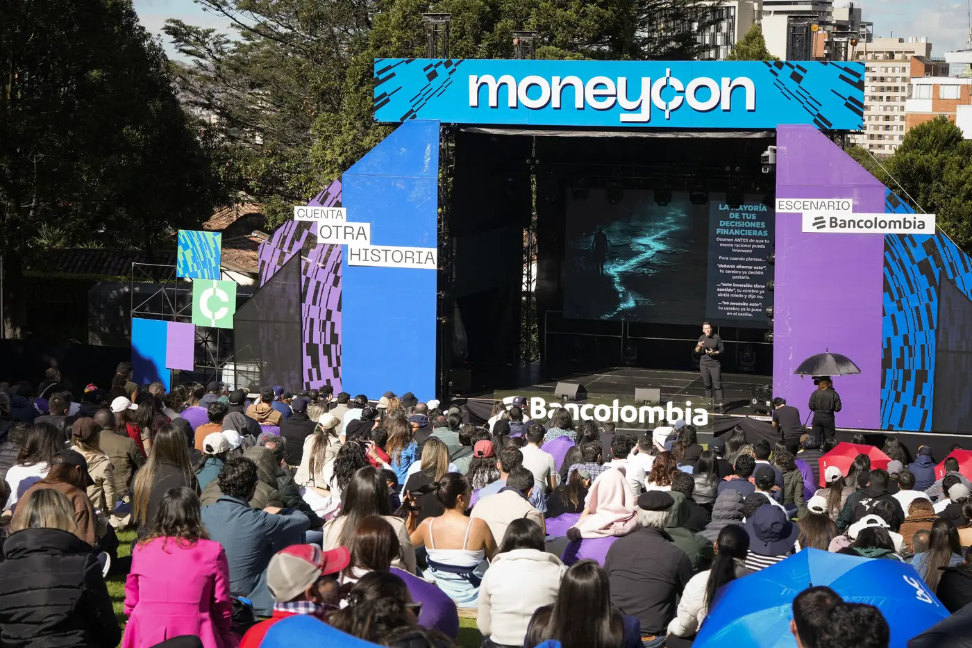 A large open-air conference in Bogota with an audience seated in front of the main stage